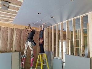image of two men hanging blueboard on a ceiling