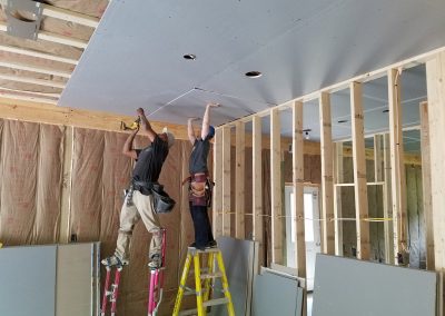 image of two men hanging blueboard on a ceiling